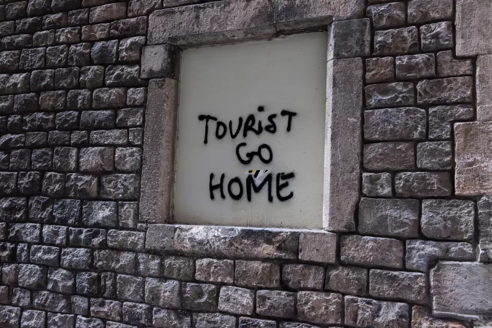 Spray painted words "Tourist Go Home" on wall in Barcelona illustrate locals' frustration with overtourism.